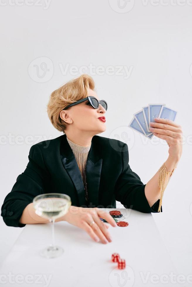 mujer madura y elegante con esmoquin negro y gafas de sol feliz de ganar en el casino. juegos de azar, moda, concepto de hobby. foto