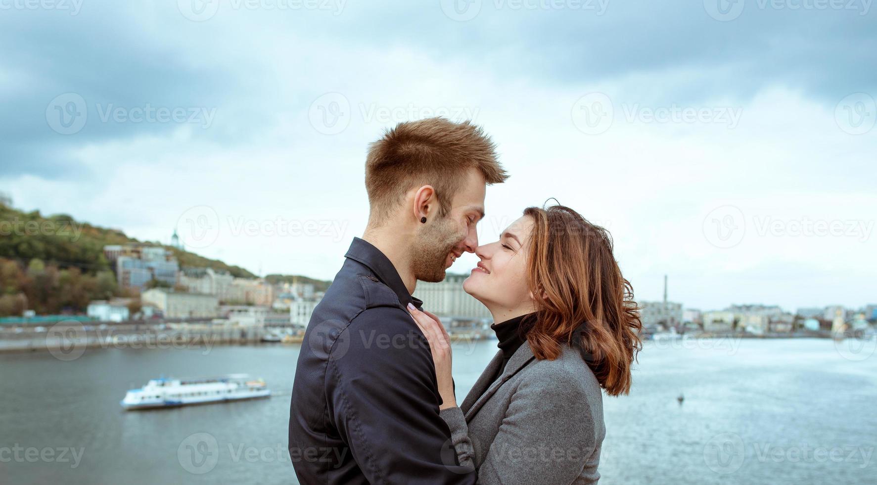 hermosa increíble divertida alegre pareja joven abrazándose al aire libre junto al río en el fondo del puente. novia y novio. concepto de familia, amor y amistad foto