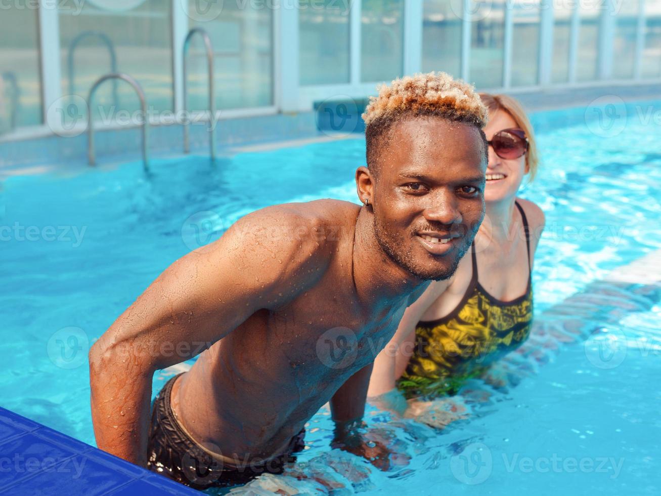 hombre afroamericano con mujer caucásica en la piscina. verano. concepto de vacaciones, diversidad y deporte. foto