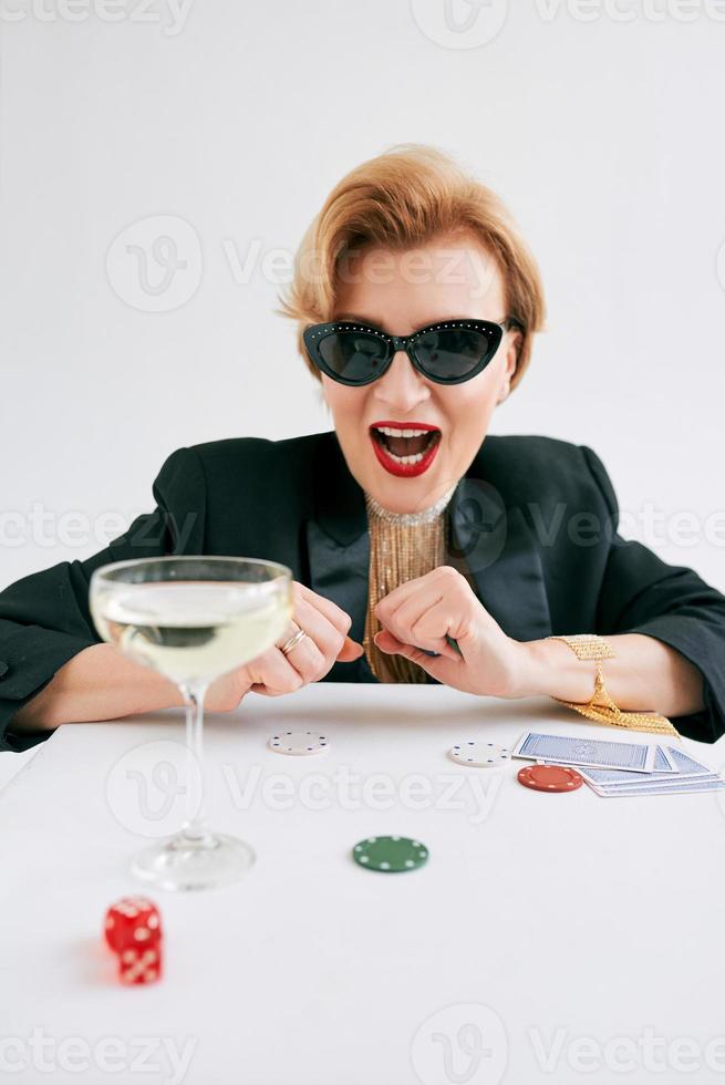 mature stylish woman in black tuxedo and sunglasses happy to win in casino. Gambling, fashion, hobby concept. photo