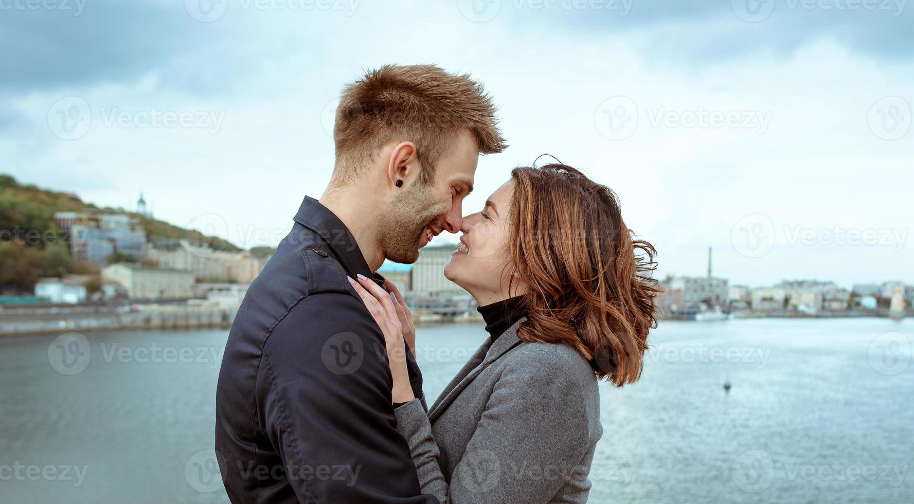 hermosa increíble divertida alegre pareja joven abrazándose al aire libre junto al río en el fondo del puente. novia y novio. concepto de familia, amor y amistad foto