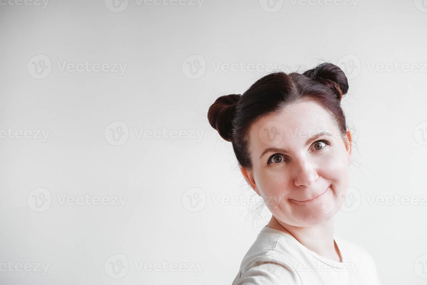 mujer con coletas y una cara graciosa con una camiseta sobre un fondo blanco. copia, espacio vacío foto