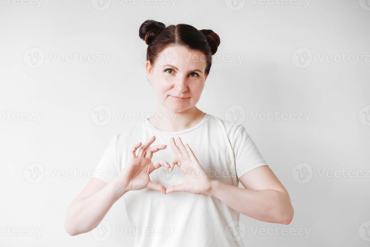 Portrait of beautifull woman with pigtails holding forefinger on her lips while standing over white backgrounnd, asking to keep secret. Copy, empty space photo