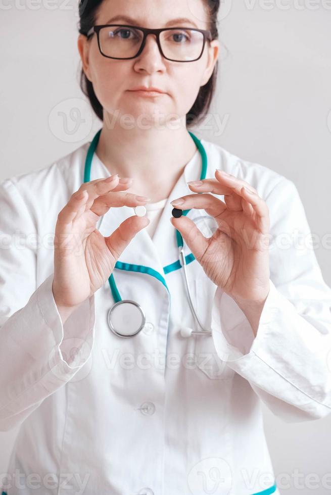 Woman doctor with pills in her hands on a white background. Taking vitamins or medications. Copy, empty space for text photo