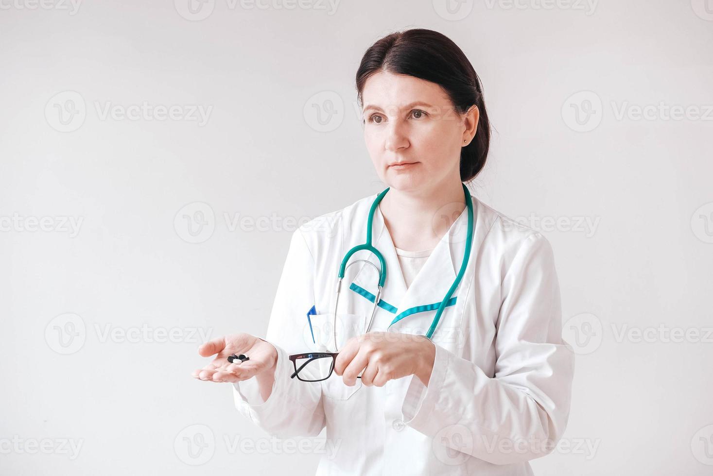 Woman doctor with pills in her hands on a white background. Taking vitamins or medications. Copy, empty space for text photo