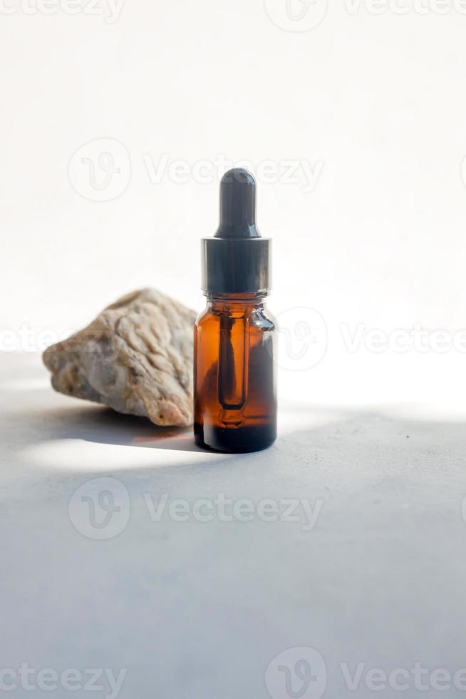 Glass dropper bottle with pipette near the stone. Cosmetic oil bottle mockup. Mockup scene. Product presentation concept. photo
