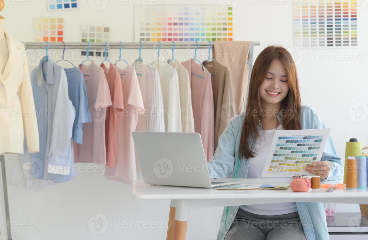 mujer diseñadora de ropa que usa una computadora portátil para dibujar un modelo de moda moderna en su tienda. foto