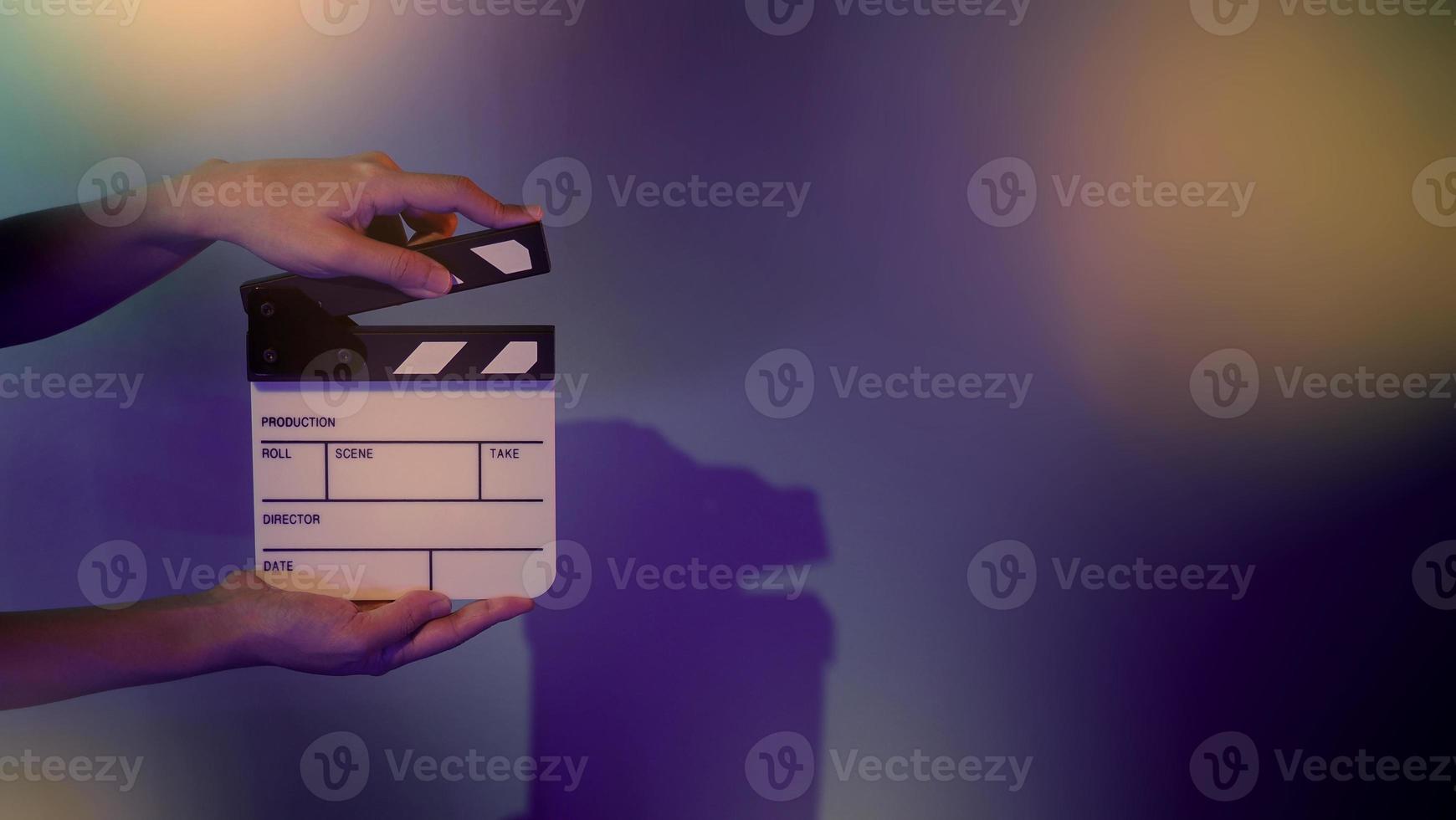 Hand holds empty film making clapperboard on color background in studio photo