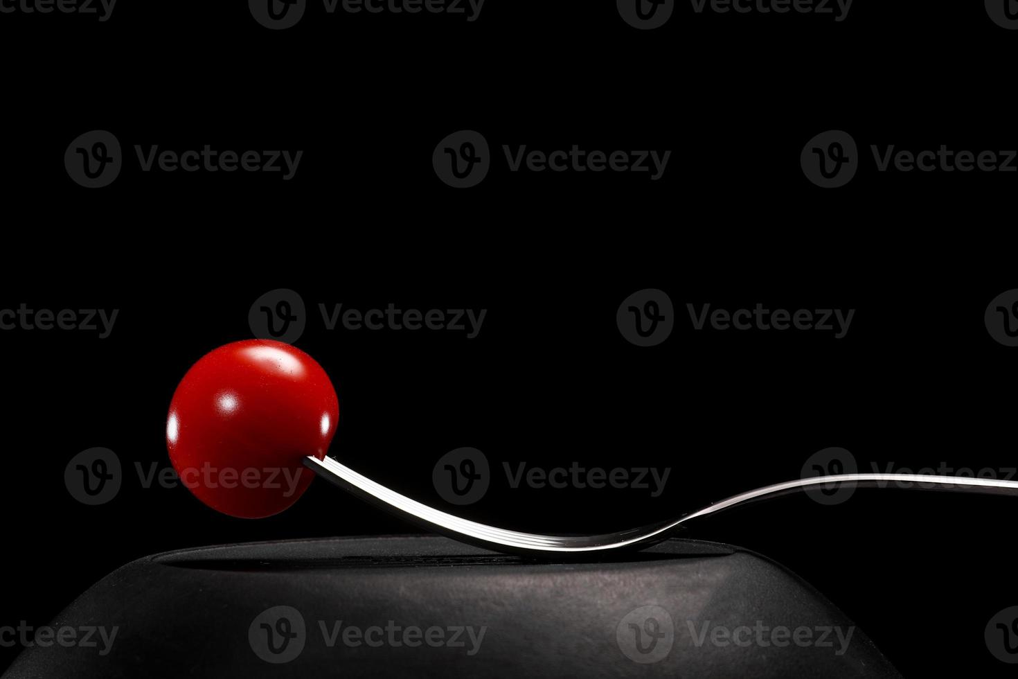 Fork with cherry tomato close-up. Isolated image on a black background. Macro photo. cooking concept photo
