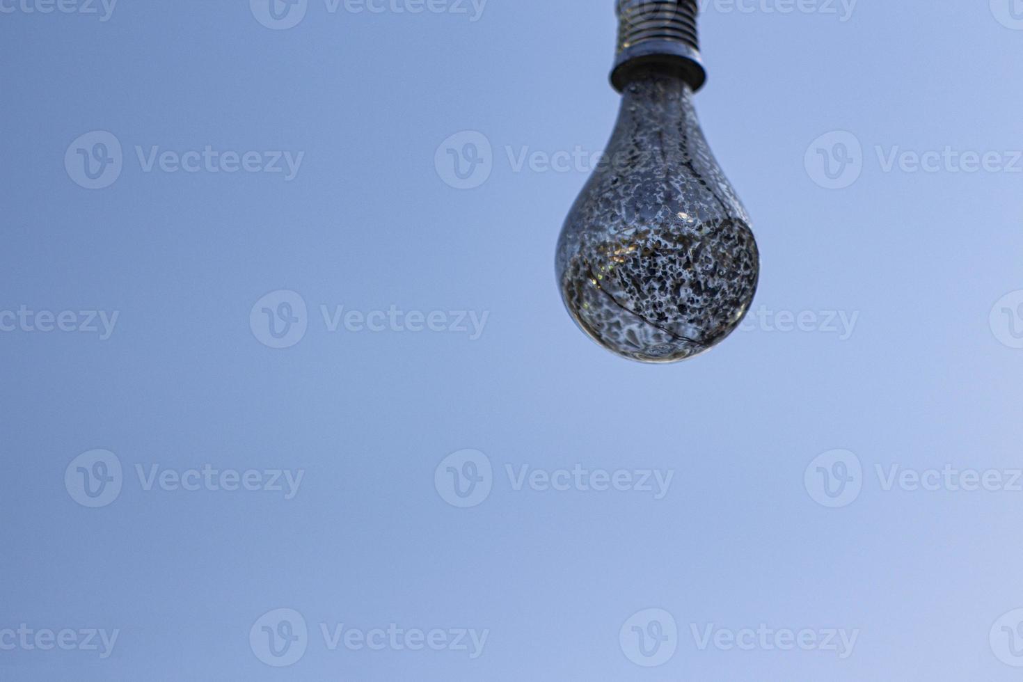 A light bulb against a blue sky. Close up the light bulb. Blue sky background. Decorative light bulb. photo