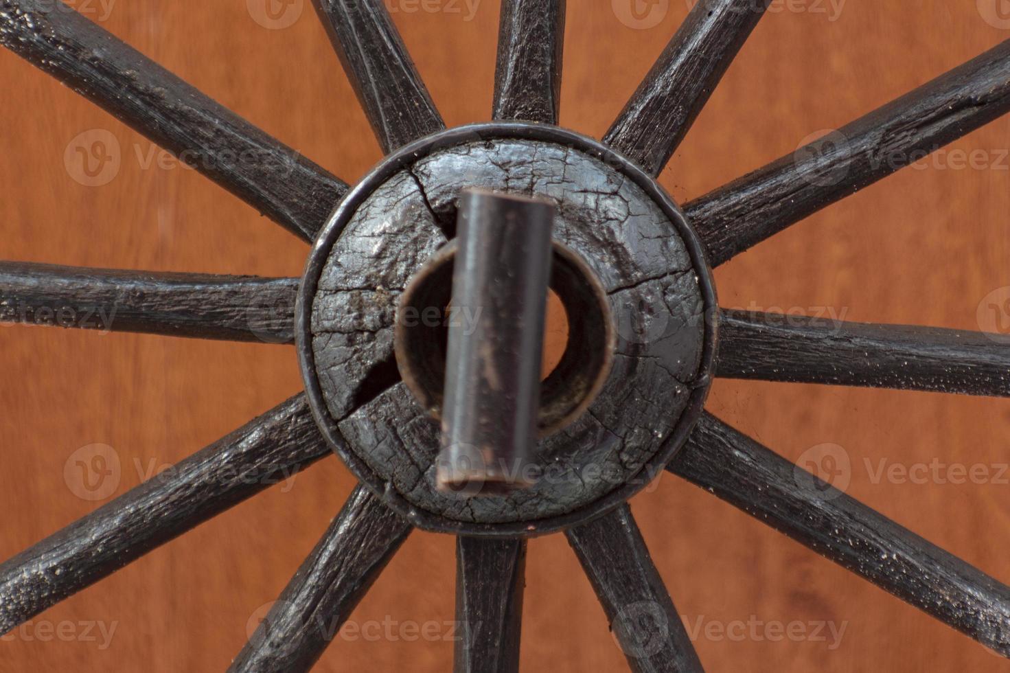 Detail Of Wooden Wagon Wheel, Cartwheels close up from the center, Forgotten old Wooden Wagon Wheel Leaning Against a Wooden Wall. Cartwheels at the old wood wall. photo