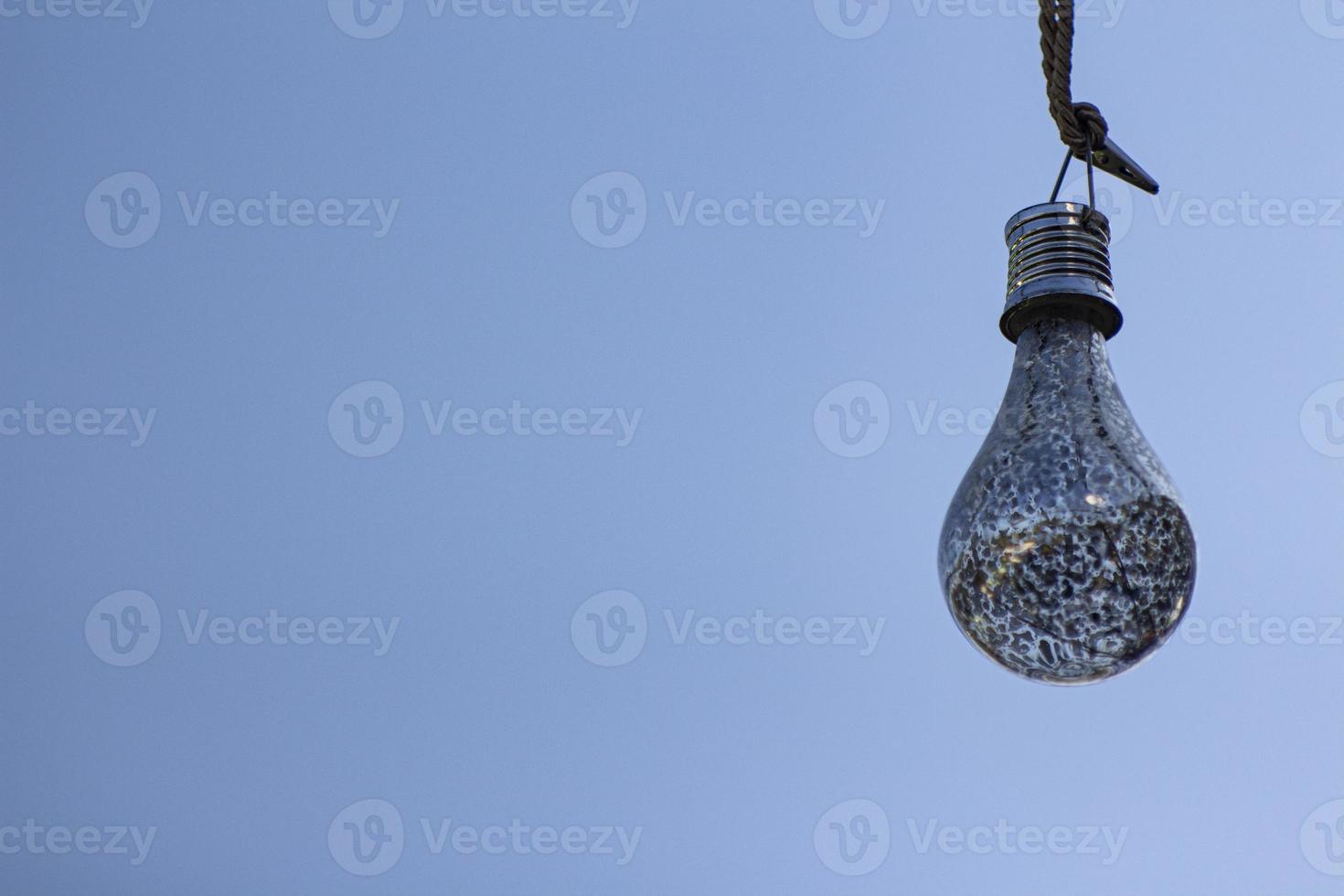 A light bulb against a blue sky. Close up the light bulb. Blue sky background. Decorative light bulb. photo