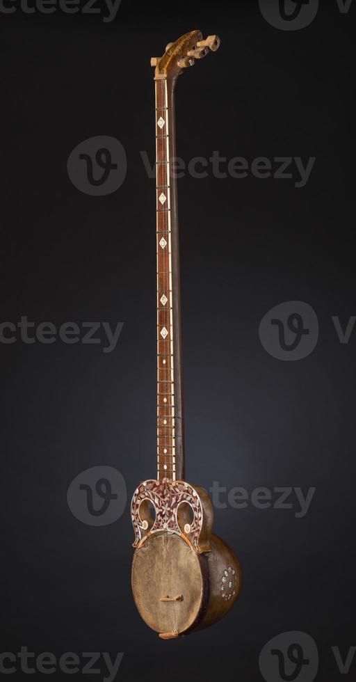 ancient Asian stringed musical instrument on black background with backlight photo