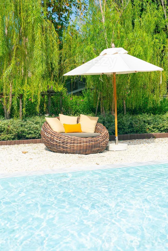 outdoor patio chair with pillow and umbrella around swimming pool photo