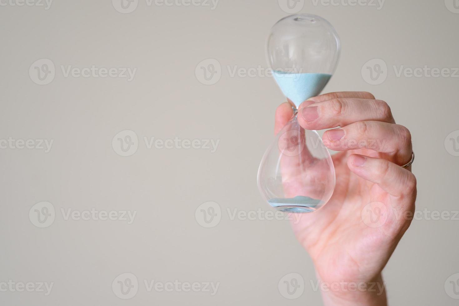 Hourglass in the hands of a man on a light background. photo