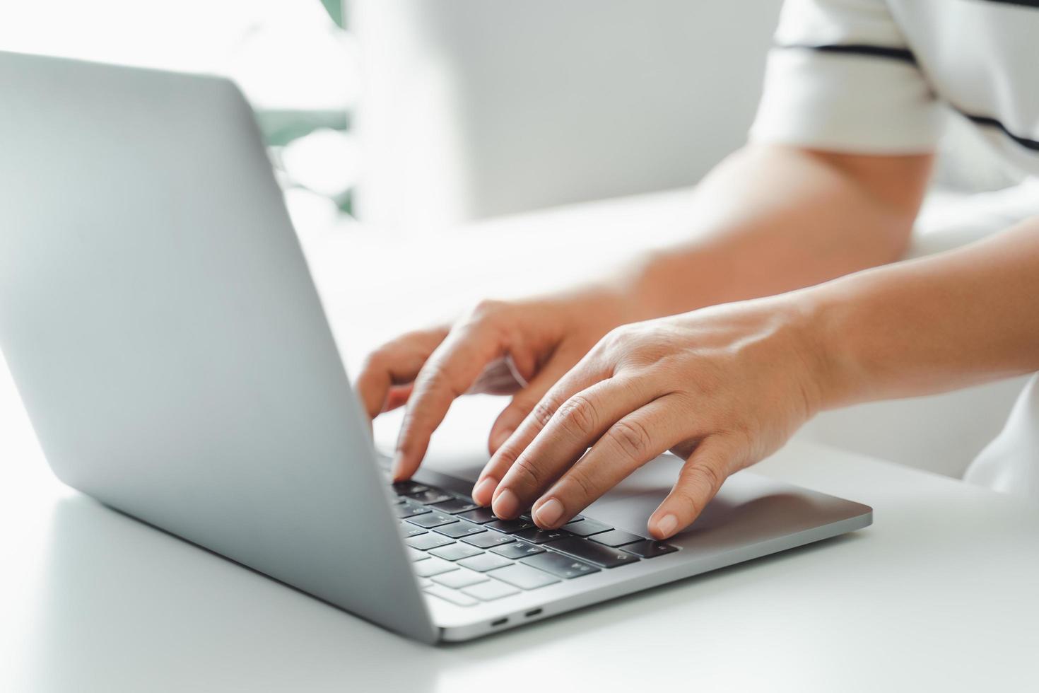 primer plano de las manos de la mujer escribiendo en el teclado de la computadora portátil en la mesa en la oficina o el lugar de trabajo. foto
