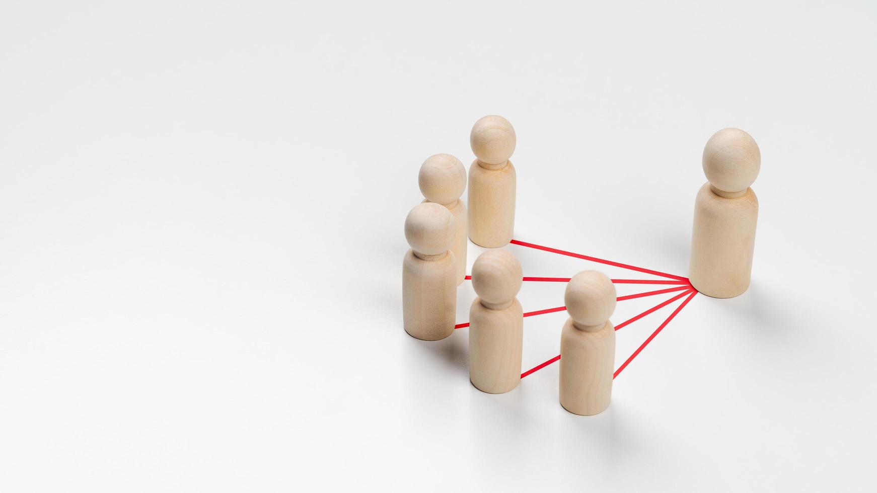 las muñecas de madera están conectadas entre sí con líneas rojas sobre fondo blanco. trabajo en equipo, liderazgo, negocios, concepto de gestión de recursos humanos foto