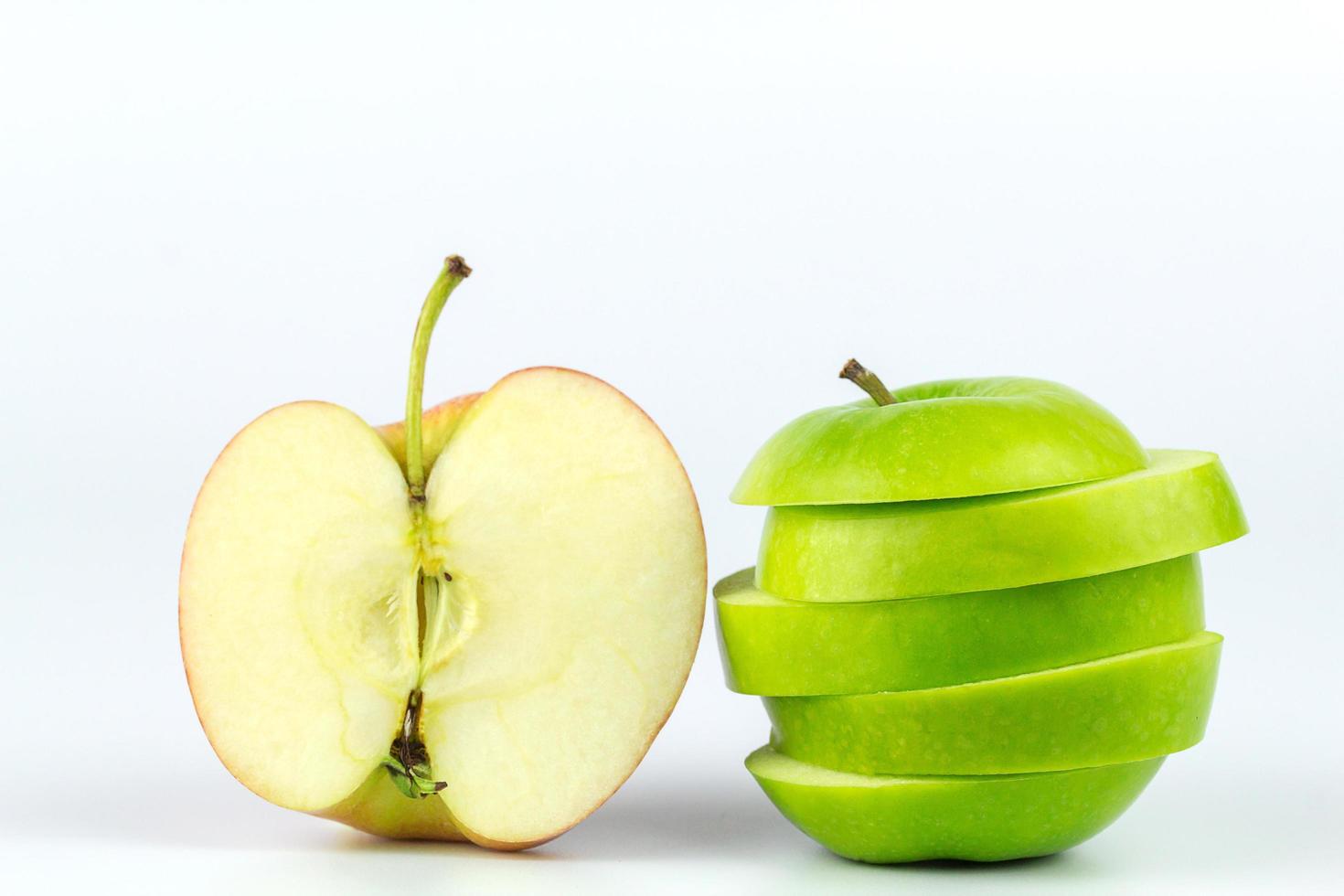 Fruta entera de manzanas verdes y rojas con una rodaja aislada de fondo blanco. foto