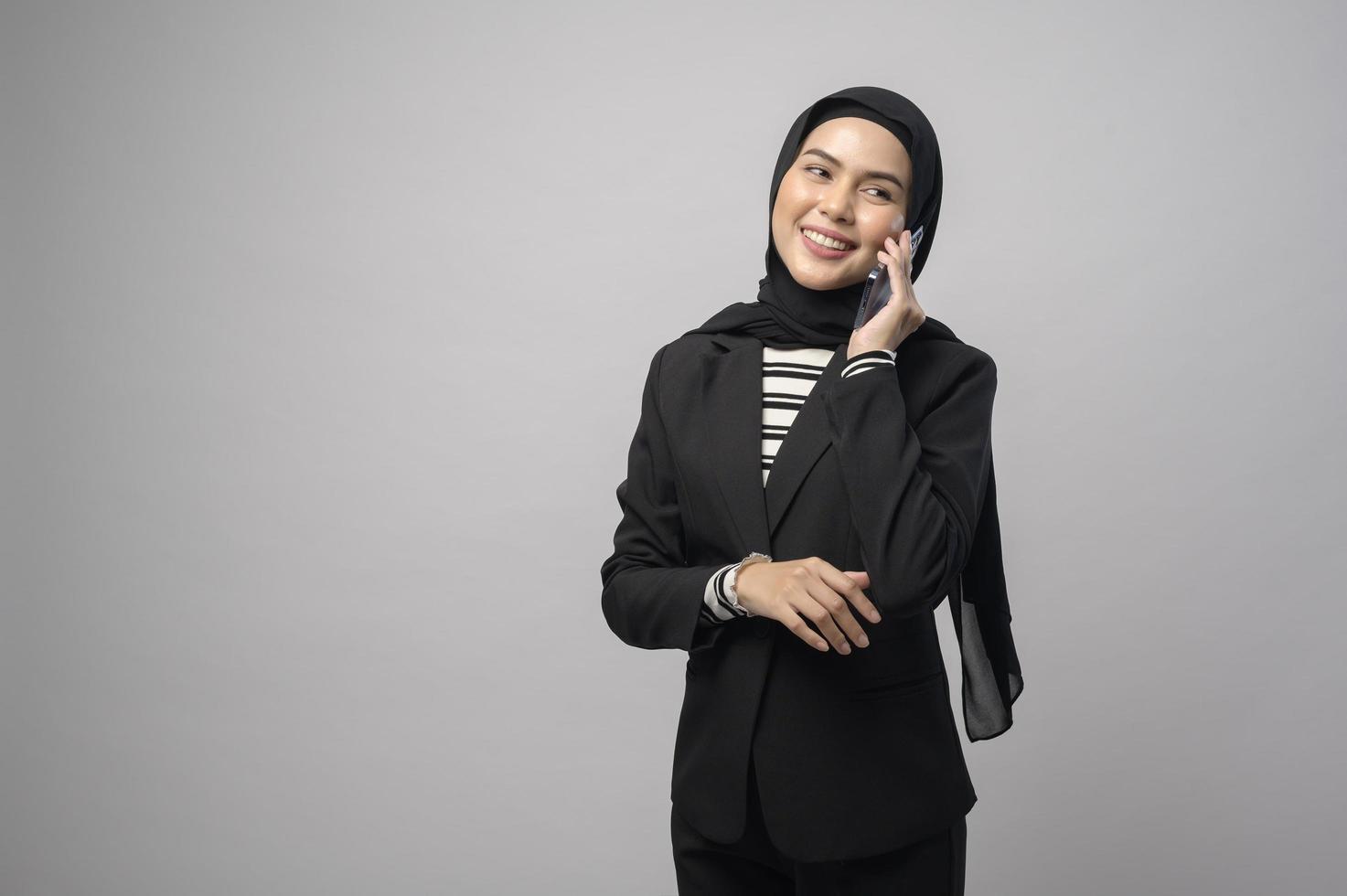 retrato de una mujer hermosa con hiyab usando un teléfono celular con fondo blanco foto