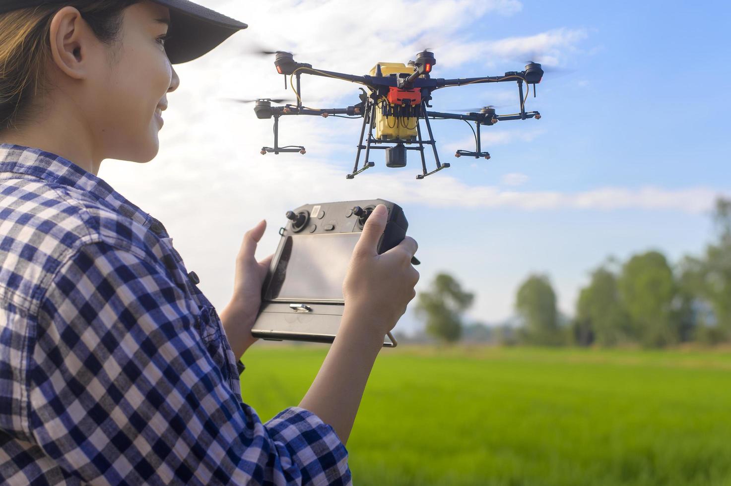 Young smart farmer controlling drone spraying fertilizer and pesticide over farmland,High technology innovations and smart farming photo