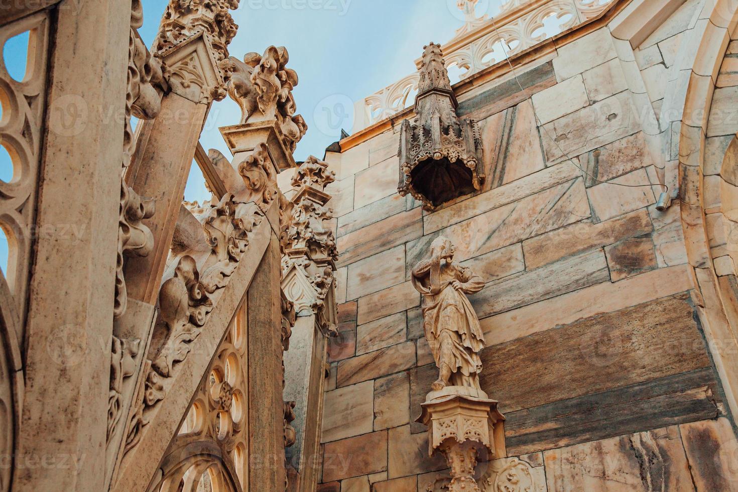 Roof of Milan Cathedral Duomo di Milano with Gothic spires and white marble statues. Top tourist attraction on piazza in Milan, Lombardia, Italy. Wide angle view of old Gothic architecture and art. photo