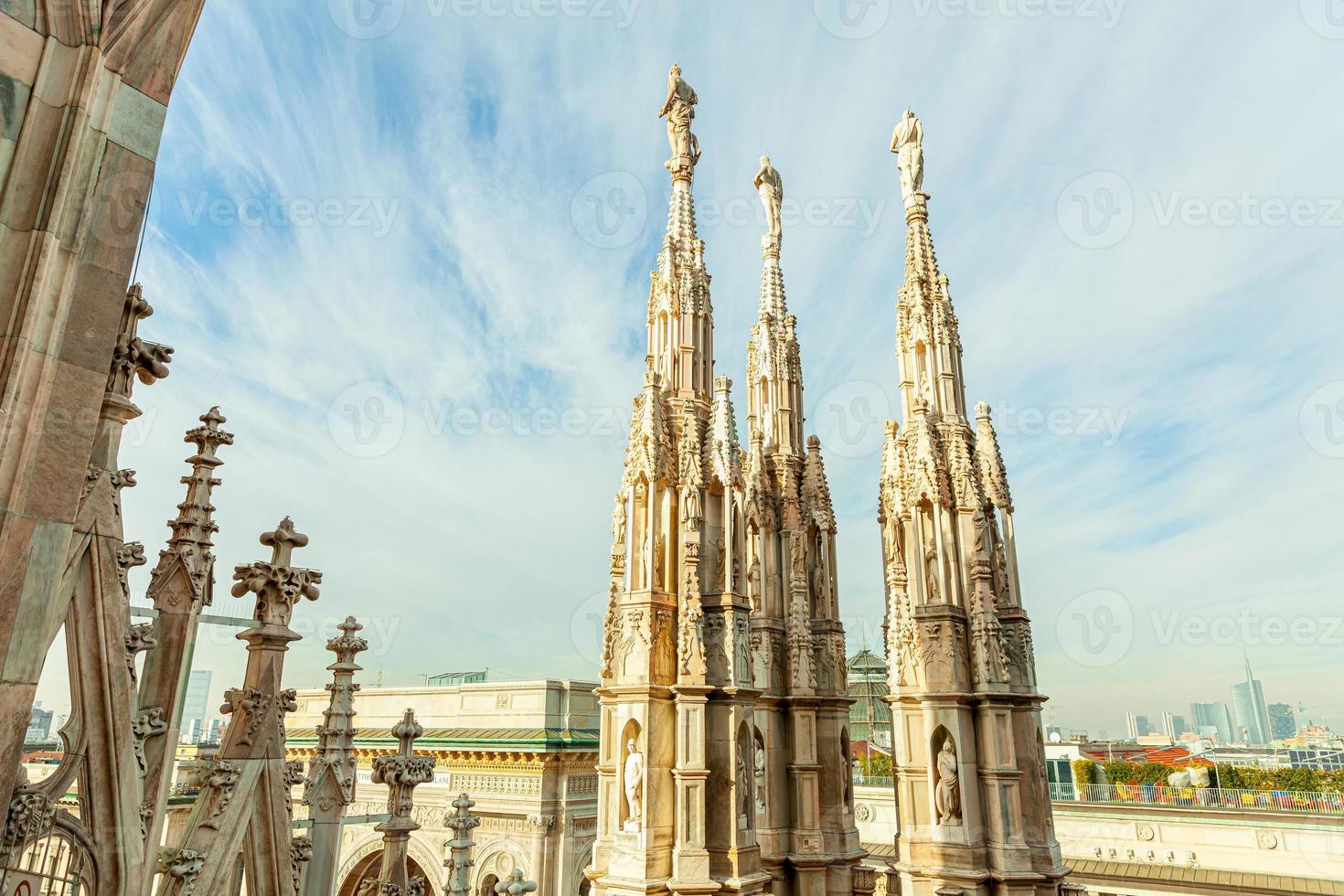 Roof of Milan Cathedral Duomo di Milano with Gothic spires and white marble statues. Top tourist attraction on piazza in Milan, Lombardia, Italy. Wide angle view of old Gothic architecture and art. photo