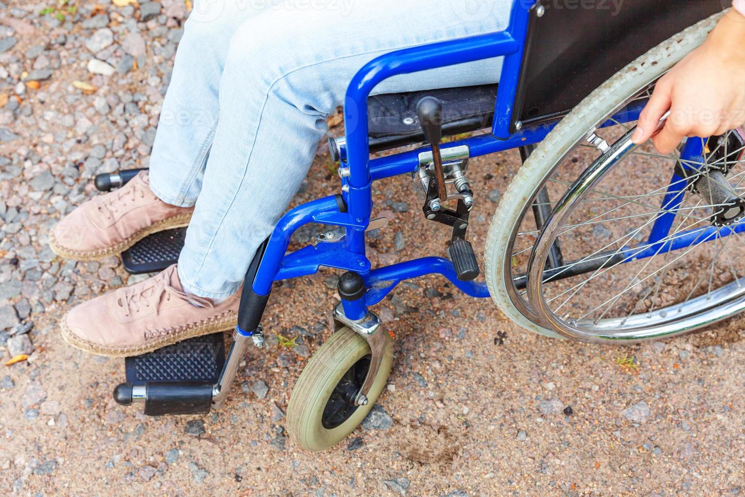 Legs feet handicap woman in wheelchair wheel on road in hospital park waiting for patient services. Unrecognizable paralyzed girl in invalid chair for disabled people outdoors. Rehabilitation concept. photo