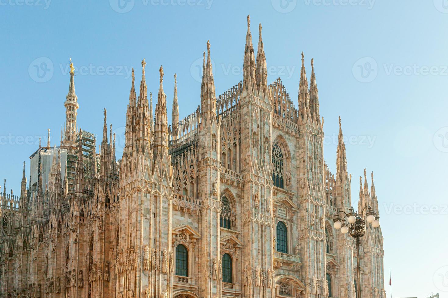 Famous church Milan Cathedral Duomo di Milano with Gothic spires and white marble statues. Top tourist attraction on piazza in Milan Lombardia Italy. Wide angle view of old Gothic architecture and art photo