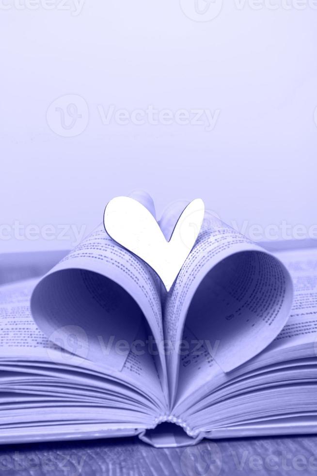 An open book with a wooden heart on the table. Concept Love for reading, books. Library, education. Closeup copy space photo