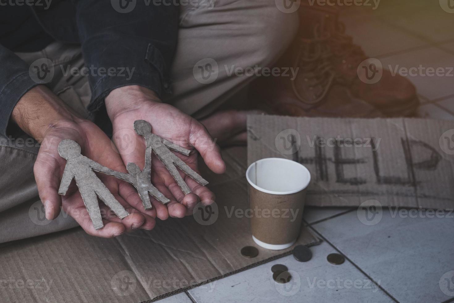 hombre adulto sin hogar sentado en la calle a la sombra del edificio y pidiendo ayuda y dinero con un cartel. concepto de personas sin hogar. foto