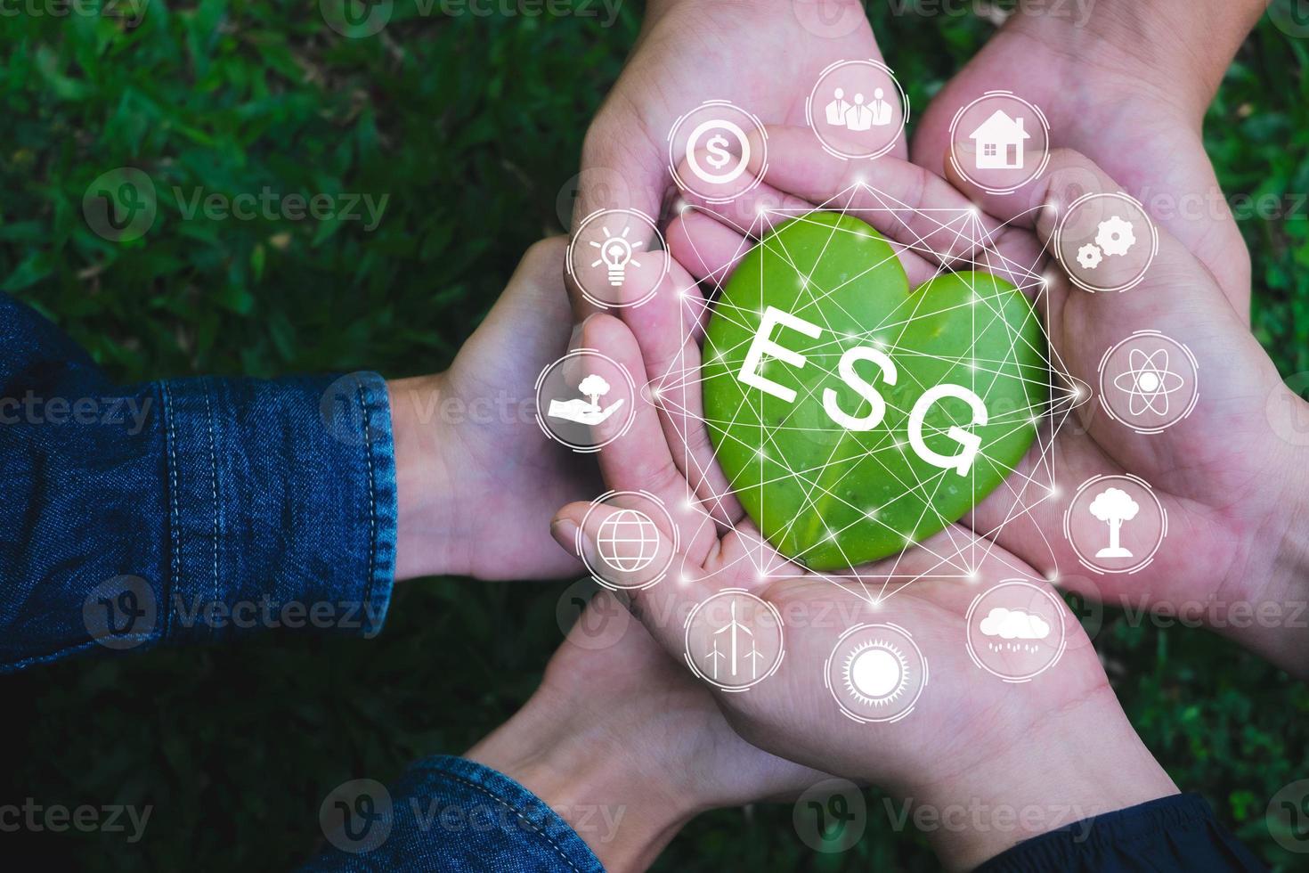 Adult hands holding green heart with ESG icon concept for environmental, social, and governance in sustainable and ethical business on the Network connection on a green background. photo