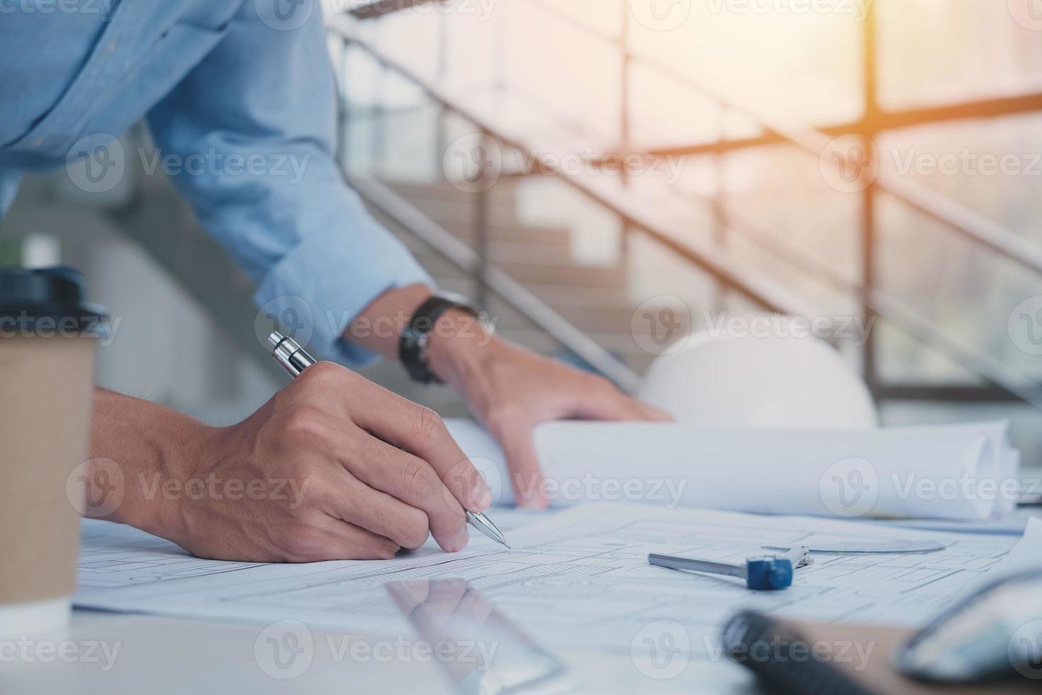 Business man construction site engineer. Engineering objects on workplace with partners interacting on background. architectural plan,sketching a construction project ,selective focus,Business concept photo