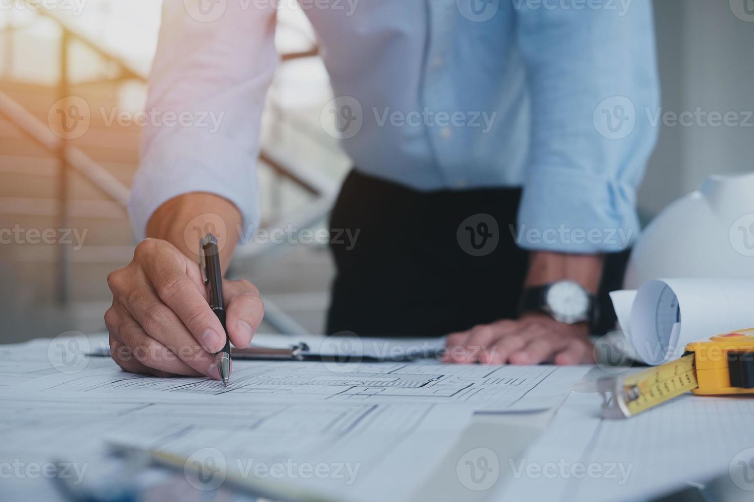 Business man construction site engineer. Engineering objects on workplace with partners interacting on background. architectural plan,sketching a construction project ,selective focus,Business concept photo