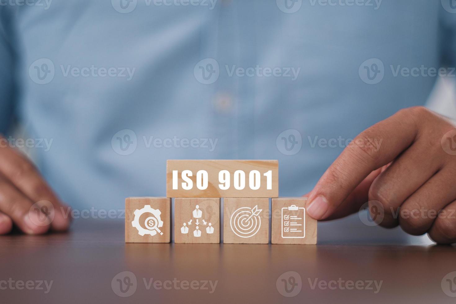 Businessman pressing his finger on the wooden cubes with the abbreviation ISO 9001. ISO quality control certification concept. photo
