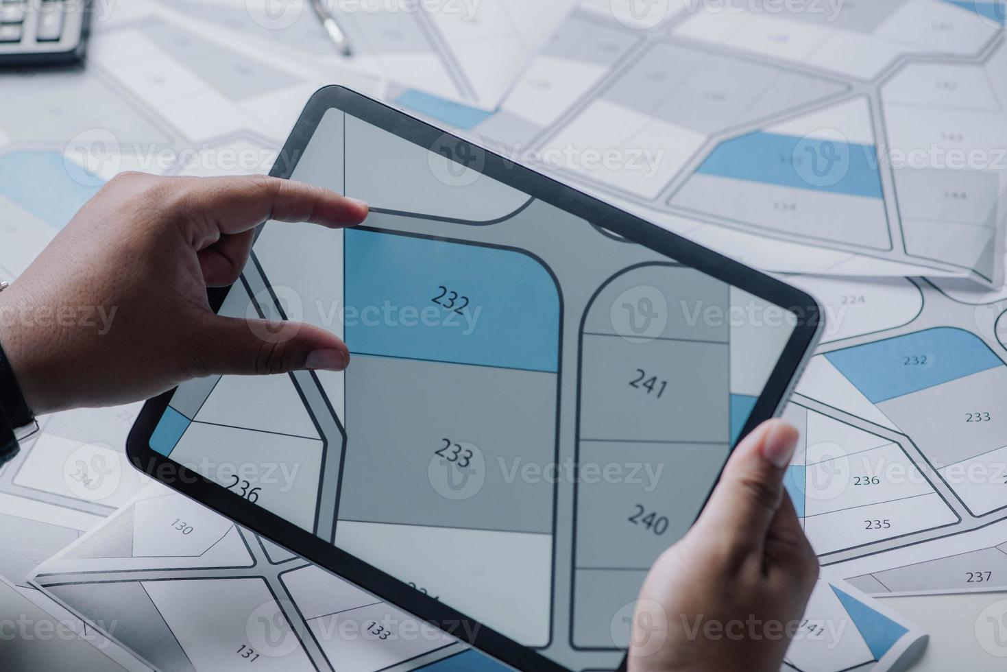 Man searching building plot to buy on cadastral plan for house construction on digital tablet. house or residential i.e. construction, development, sale, buy. photo