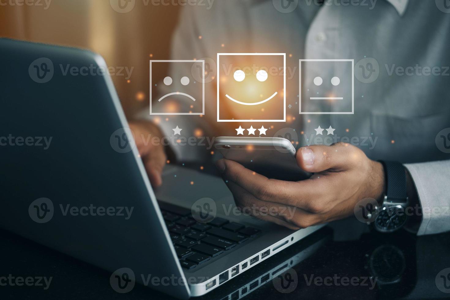 Business man holding phone wiht virtual screen on the happy Smiley face icon to give satisfaction in service. rating very impressed. Customer service and Satisfaction concept photo