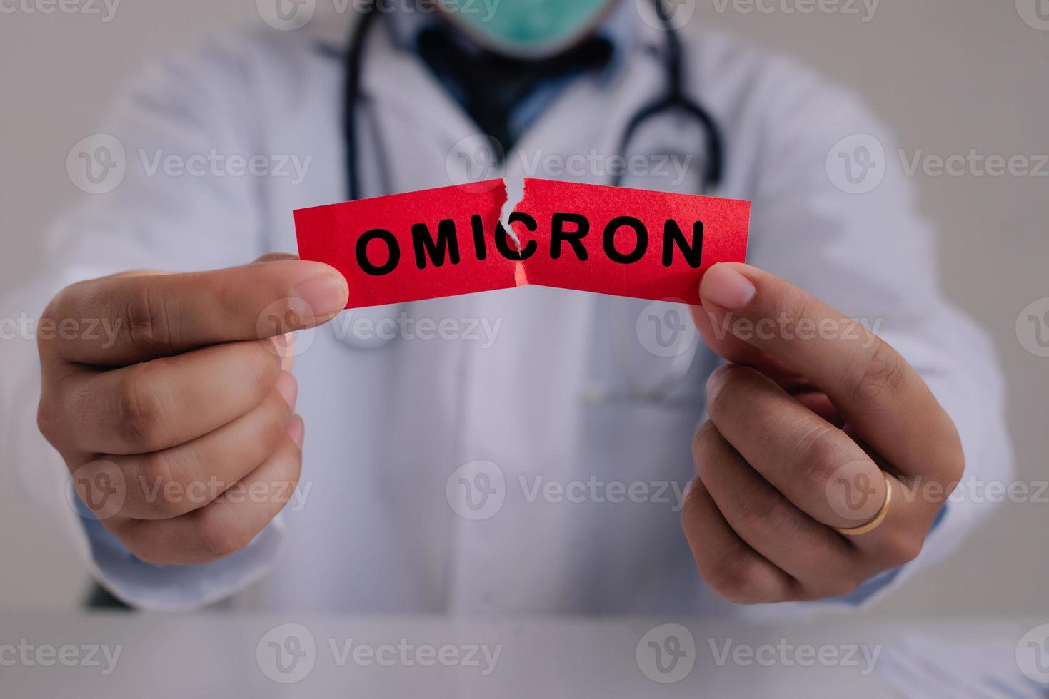 New generation vaccine against Coronavirus South African variant. Omicron variant of SARS-CoV-2. New B.1.1.529 Variant of concern. Doctor with a stethoscope Tear the red paper with the word Omicron. photo