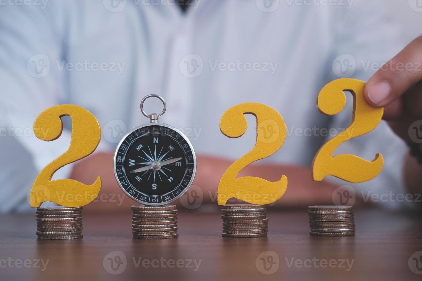 Man hands putting gold wooden number 2022 on the stack of coins compass, financial direction 2022. Tax payment, 2022 new year saving money and financial planning concept photo