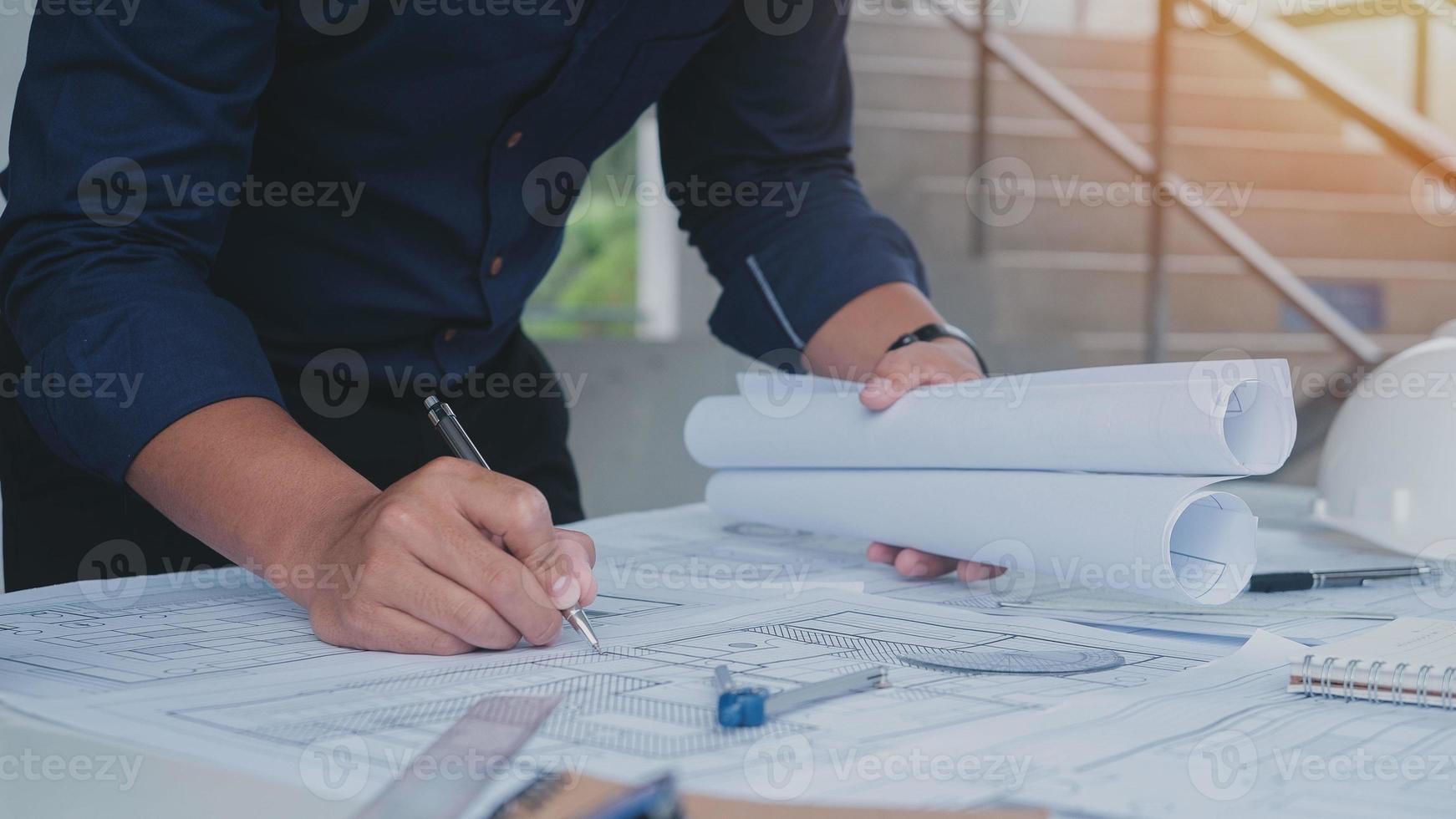 Business man construction site engineer. Engineering objects on workplace with partners interacting on background. architectural plan,sketching a construction project ,selective focus,Business concept photo