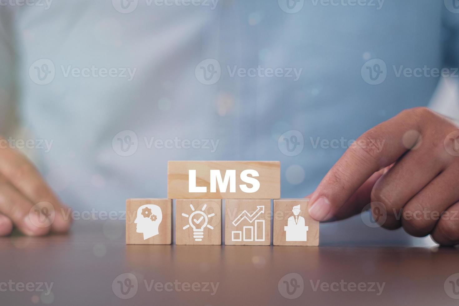 Hand holds wooden cube with LMS symbols on beautiful light background with copy space. Online business education. Electronic School. Banner and presentation. LMS Learning Management System concept. photo