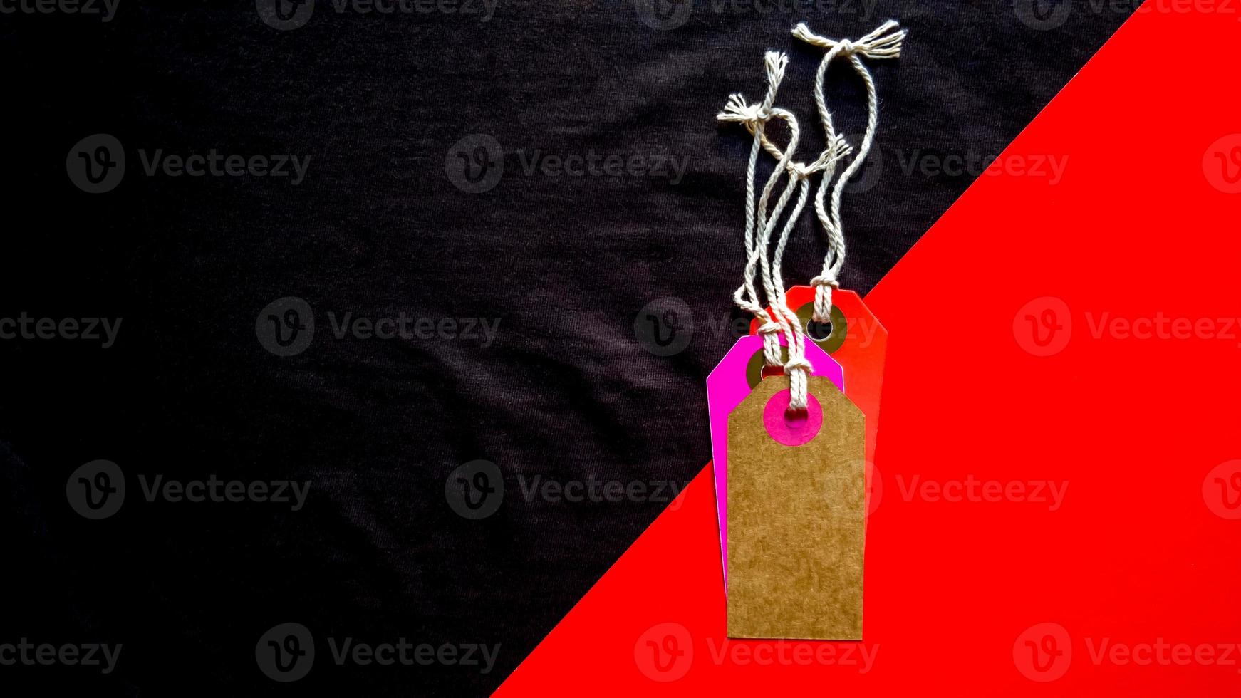 Blank tag for show price or discount on a red and black diagonal background separated. Price tags, cardboard tags in brown, purple, red. Background, holiday concept. Black Friday photo