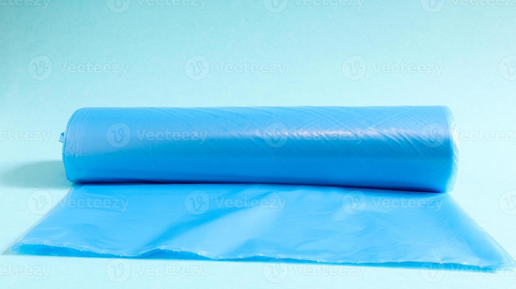 One roll of plastic garbage bags in blue on a blue background. Bags that are designed to accommodate garbage in them and used at home and placed in various garbage containers. photo