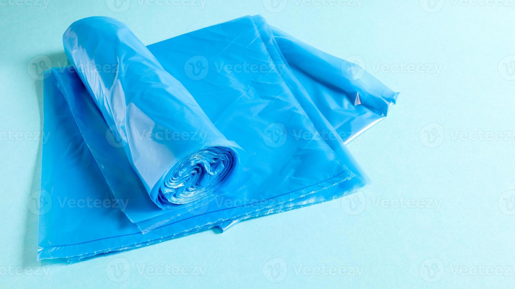 One roll of plastic garbage bags in blue on a blue background. Bags that are designed to accommodate garbage in them and used at home and placed in various garbage containers. photo