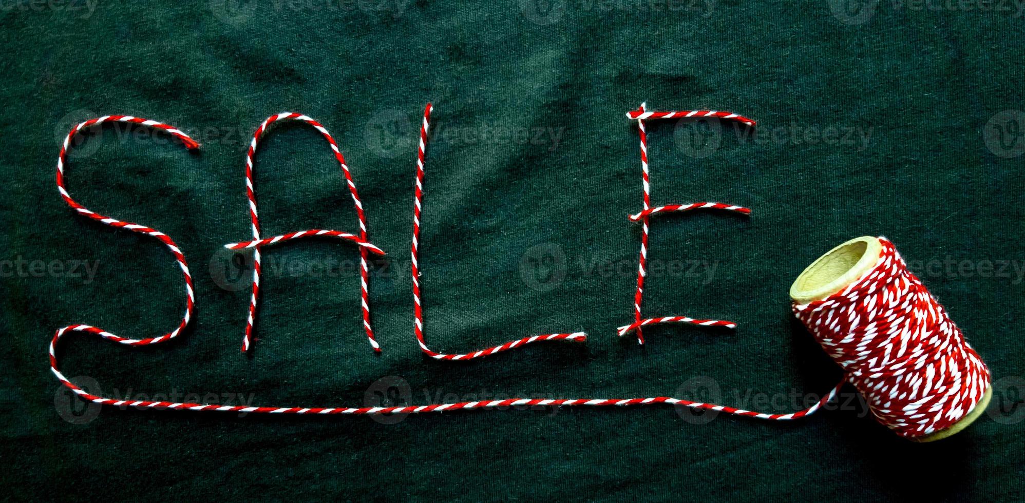 Sale, discount word made of red thread with a spool on a black background. Background, holiday concept. Black Friday - International Day of Shopping, Promotions, Discounts, Sales. photo