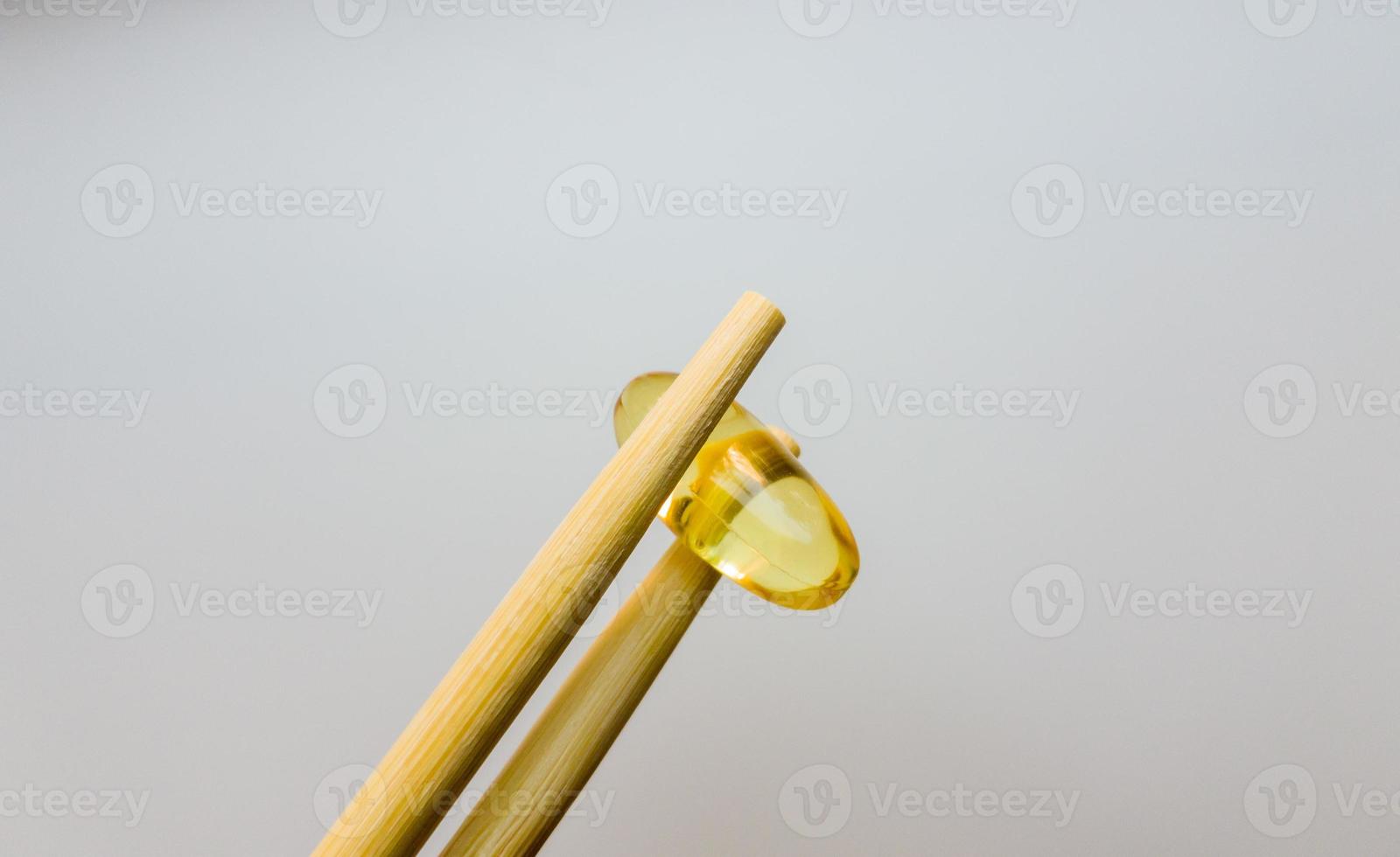 Fish oil capsules with Chinese chopsticks. Omega 3 on a white background. High Resolution Product. Food supplement. Vitamins for a healthy lifestyle. Fatty acid. Metabolism in the body. photo