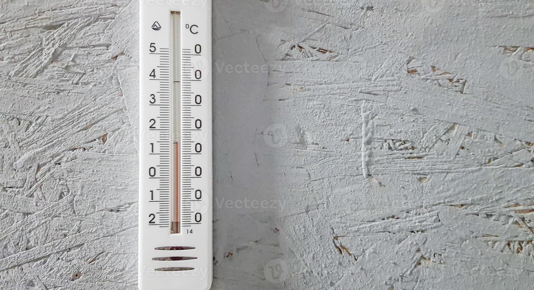white thermometer hanging on a gray gray wooden wall indoors, background with copy space and empty place for your text photo