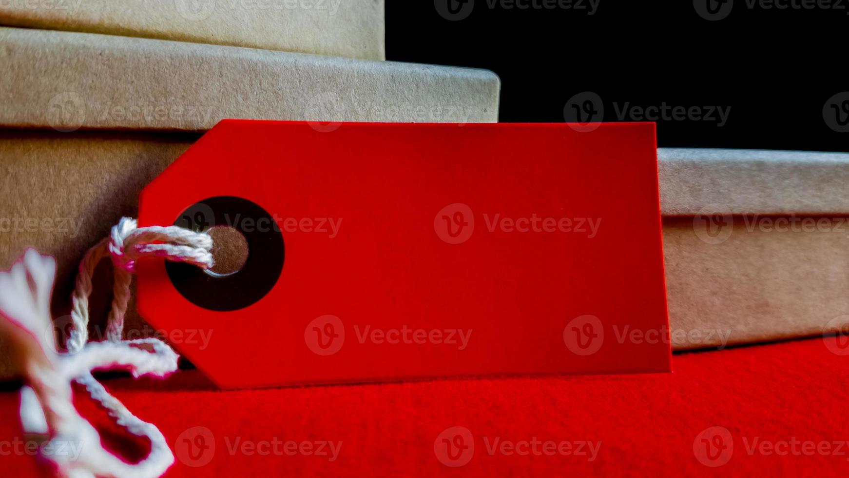 Cardboard boxes with a tag. Brown packing box with blank label and copy space on red backdrop photo