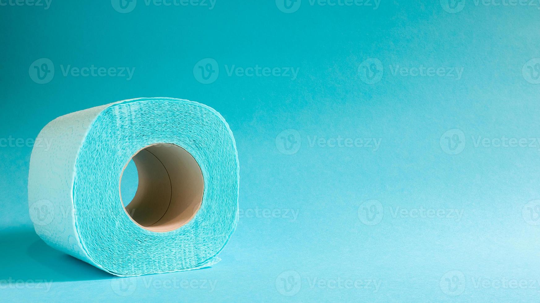 Blue roll of modern toilet paper on a blue background. A paper product on a cardboard sleeve, used for sanitary purposes from cellulose with cutouts for easy tearing. Embossed drawing. copy space. photo