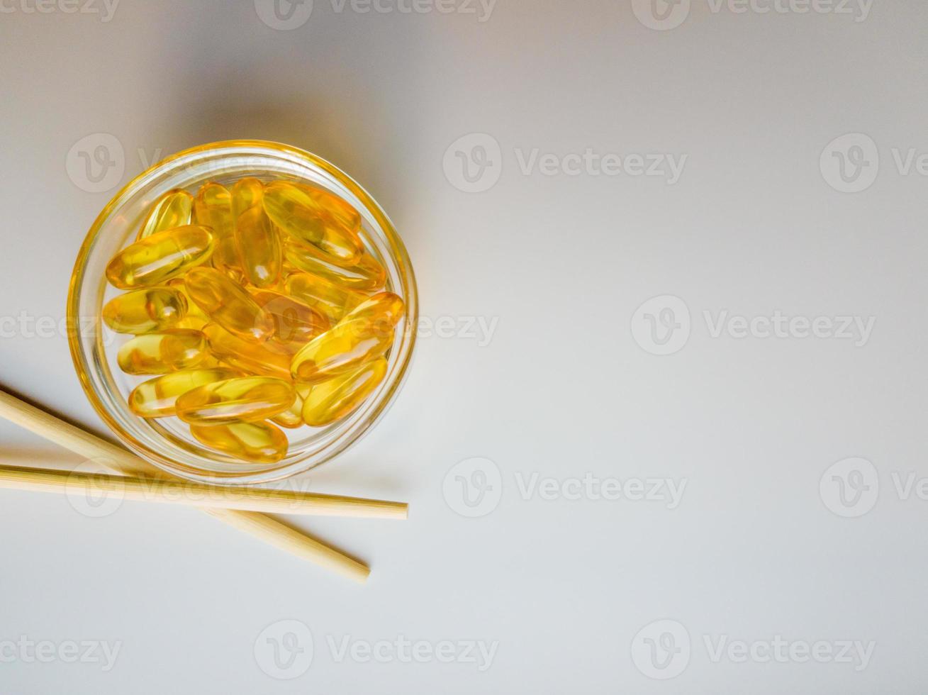 Fish oil capsules on a saucer with chopsticks. Bunch of vitamin omega 3 pills on a white background. Close-up, top view, high resolution product. Metabolism in the body. Body calcium. photo