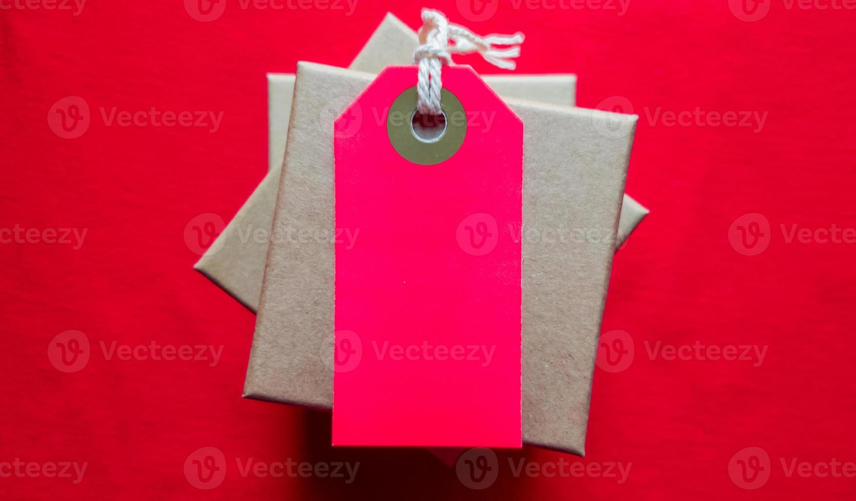 Cardboard boxes with a tag. Brown packing box with blank label and copy space on red backdrop photo